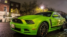 Ярко-зеленый Ford Mustang у обочины ночного городка